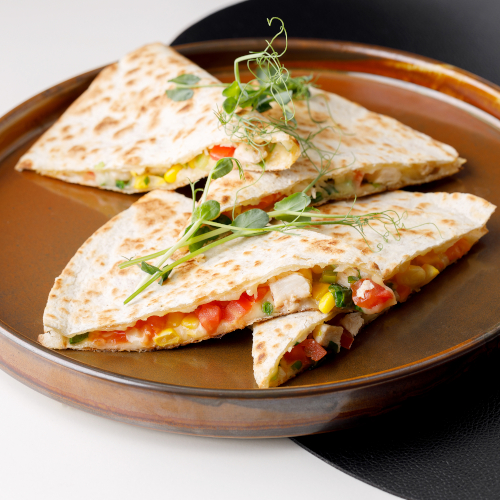 Mexican tortilla with chicken fillet, corn, tomatoes, green onions and cheese